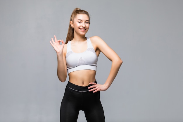 Free photo attractive woman with okay in gym attire in her outstretched arms isolated