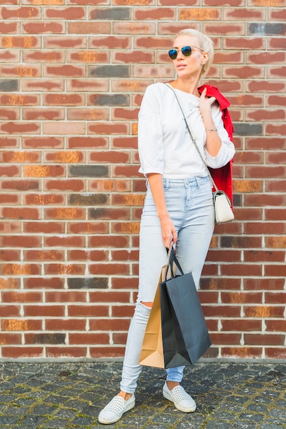 Attractive woman with packets near wall