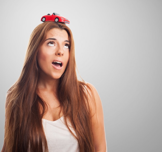 Free photo attractive woman with a small car atop her head