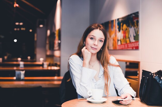 カフェでスマートフォンを持つ魅力的な女性