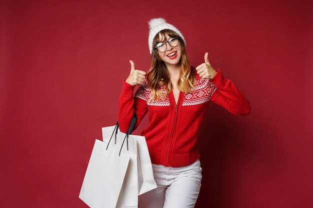 Attractive woman with wavy hairs standing with white shopping bags