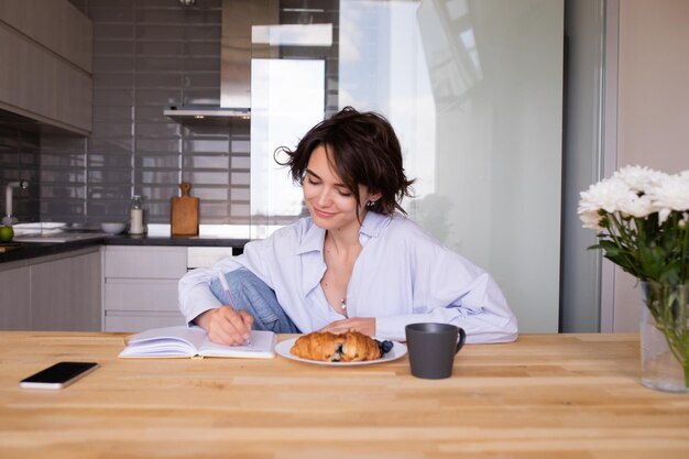 attractive woman working at home with breakfast