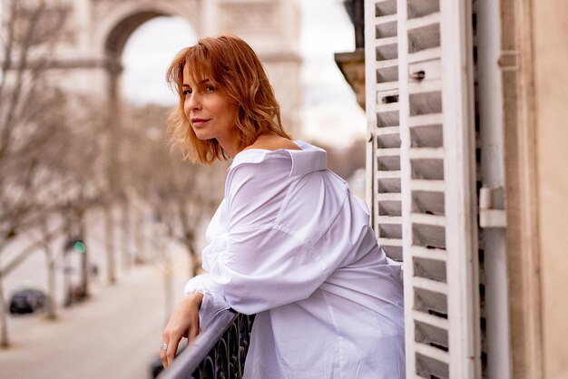 Attractive  yang woman in pajama is drinking coffee on balcony in the morning in city Paris. view of the triumphal arch.