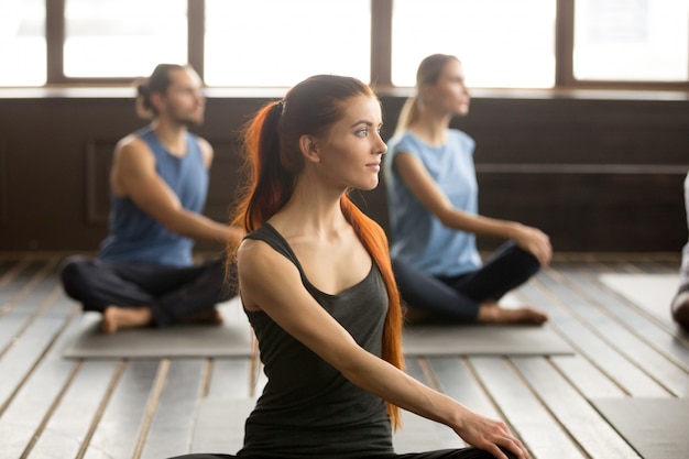 Attractive yogi woman and a Group of people in Matsyendrasana