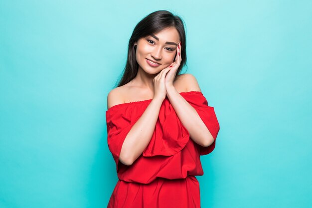 Attractive young asian woman in red dress isolated on green wall