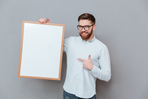 Attractive young bearded businessman holding blank