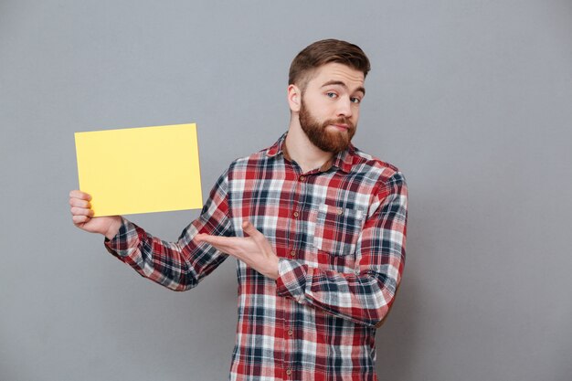 Attractive young bearded man holding blank paper