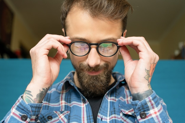 Attractive young bearded man with rose tattoo wearing eyeglasses