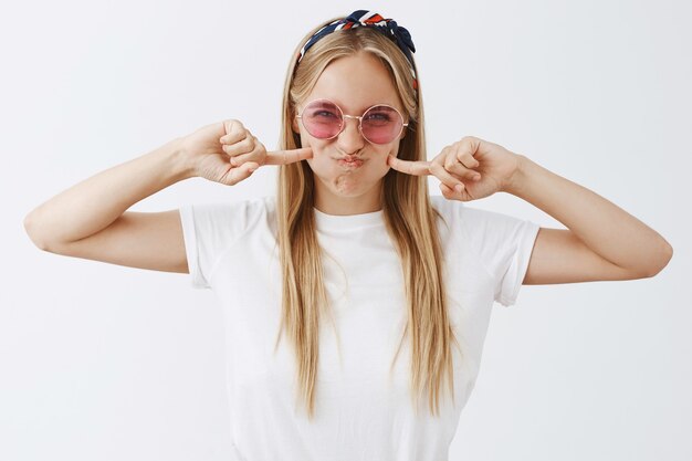 Attractive young blond girl posing against the white wall