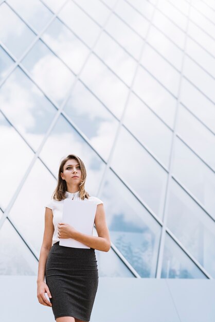 An attractive young blonde businesswoman holding document in hand