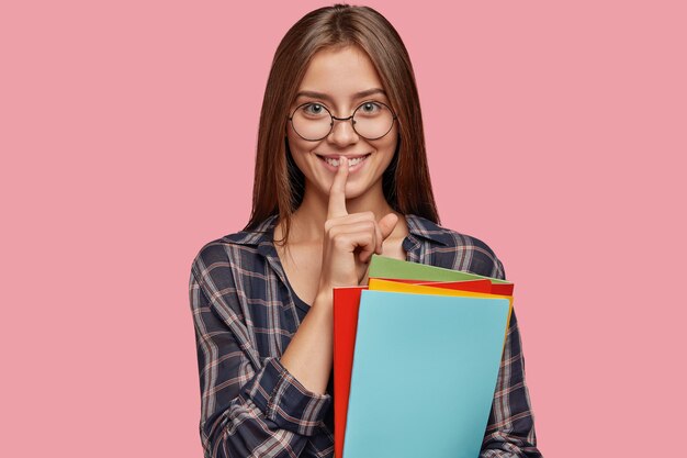 attractive young businesswoman posing against the pink wall with glasses