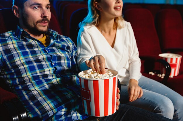 Attractive young caucasian couple watching a film at a movie theater, house or cinema.