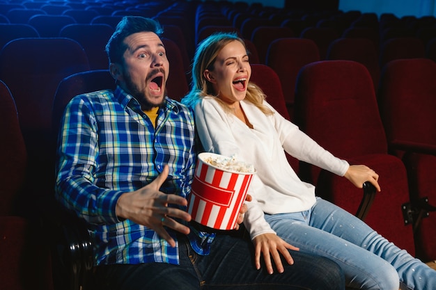 Free photo attractive young caucasian couple watching a film at a movie theater, house or cinema.