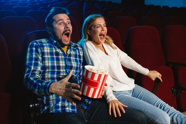 Attractive young caucasian couple watching a film at a movie theater, house or cinema.