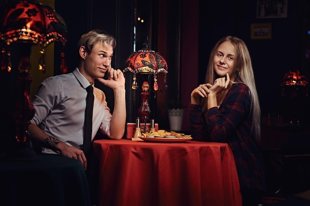 Attractive young couple eating nachos during dating at mexican restaurant.