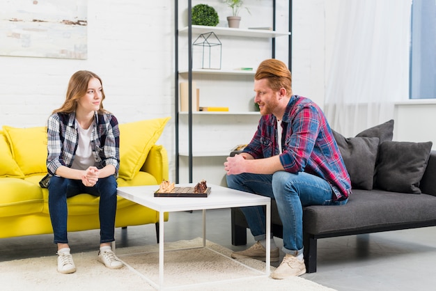 An attractive young couple looking at each other with chess board on table