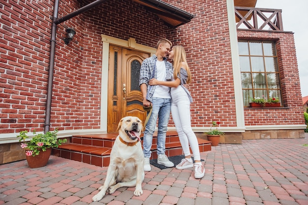 Attraente giovane coppia con labrador davanti alla loro nuova bella casa