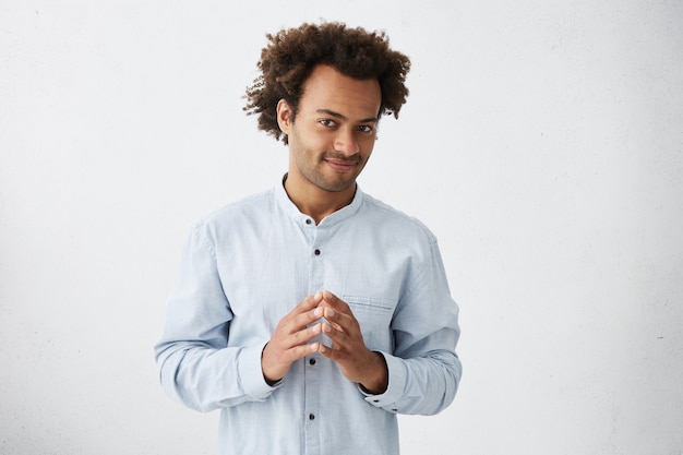 Attractive young employee with stubble and stylish haircut standing at blank wall