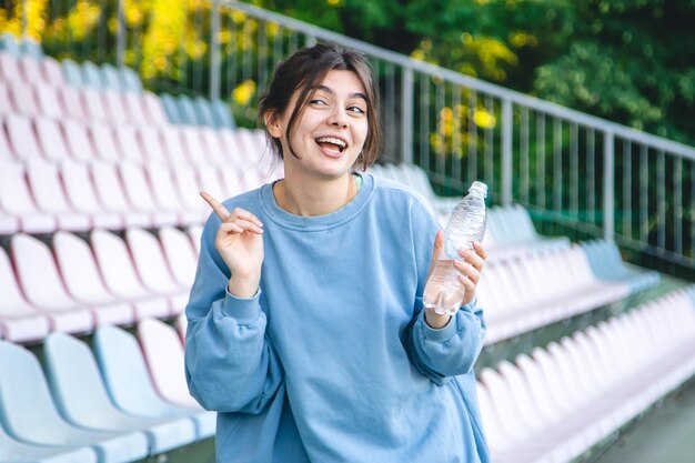 Attractive young female athlete drinks water after a workout