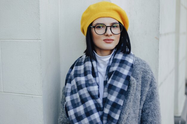 Attractive young girl in glasses in coat and yellow 