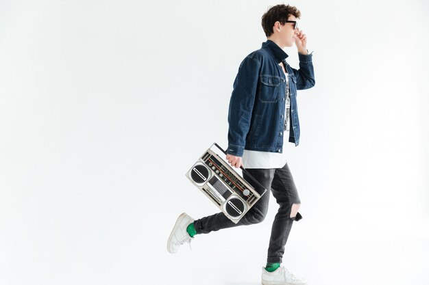 Attractive young man holding boombox. Looking aside.