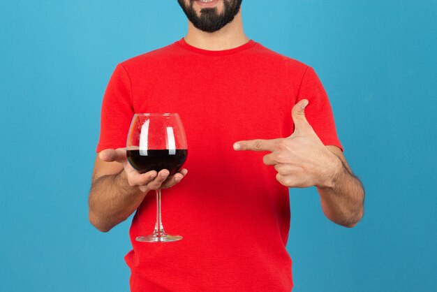 Attractive young man pointing at a glass of red wine . 