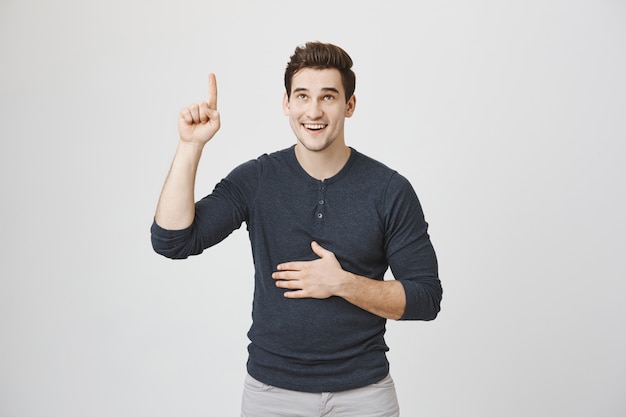 Attractive young man pointing and looking up, smiling