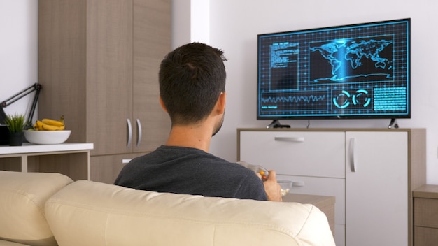 Free photo attractive young man sitting on his couch and playing video games. relaxing being home.