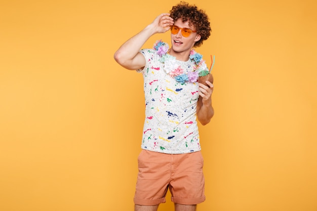 Free photo attractive young man in sunglasses holding coconut cocktail