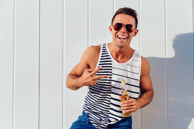 Free photo attractive young man in sunglasses showing two fingers, peace gesture