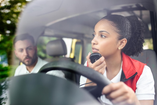 救急車に座って目をそらしている魅力的な若い救急車救急車で電話に出る若い女性彼女は同僚と一緒にいます