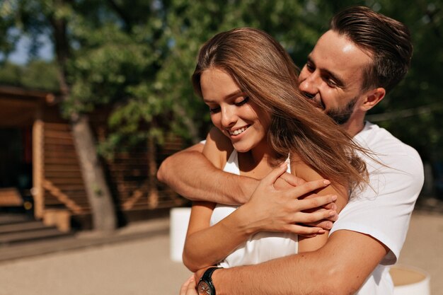 Attractive young people hugging and kissing in sunlight on the beach