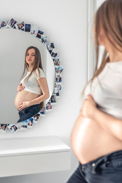 Attractive young pregnant woman in mirror reflection at home