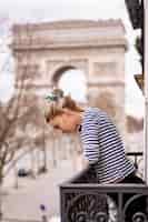 Foto gratuita attraente giovane donna sul balcone al mattino nella città di parigi. veduta dell'arco trionfale.