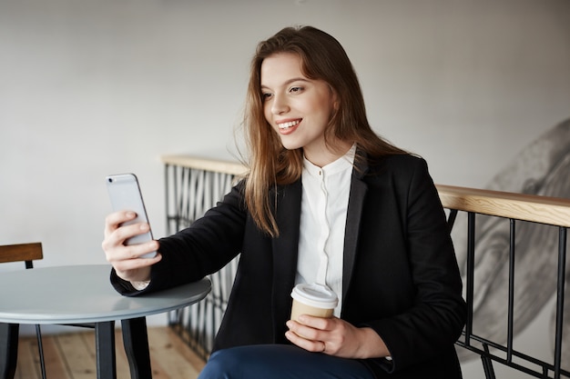 Giovane donna attraente al caffè con lo smartphone