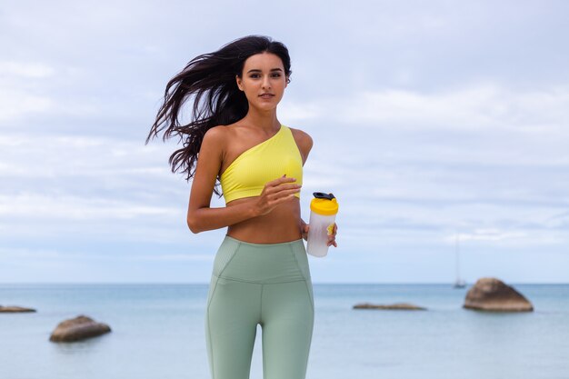 Attractive young woman in colorful sport wear on beach