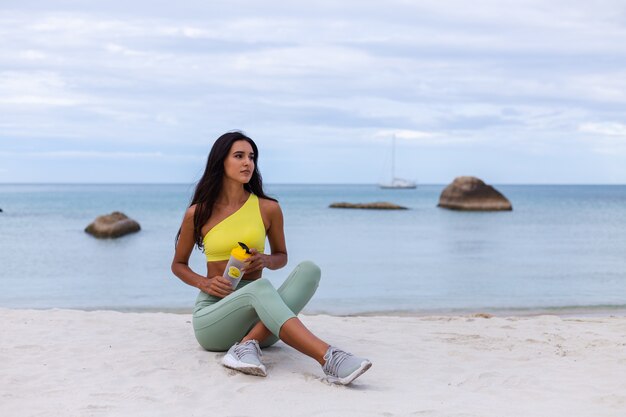 해변에서 다채로운 스포츠 착용에 매력적인 젊은 여자