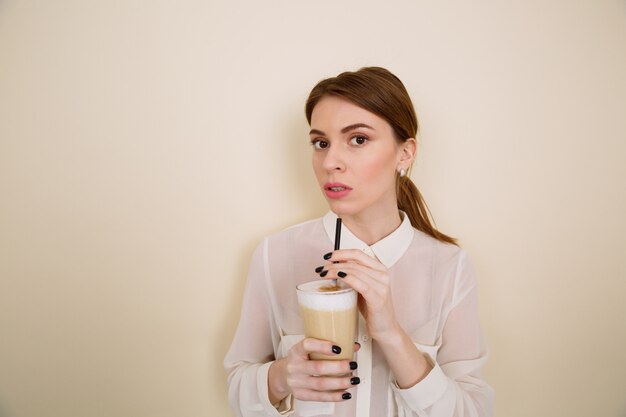 Attractive young woman drinking coffee latte from glass with straw