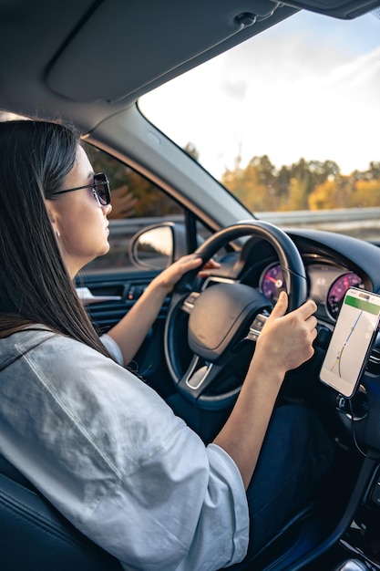 Foto gratuita una giovane donna attraente che guida un'auto usa un navigatore