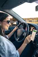 Free photo an attractive young woman driving a car uses a navigator