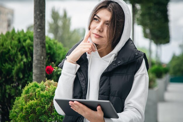 外でタブレットを保持している魅力的な若い女性