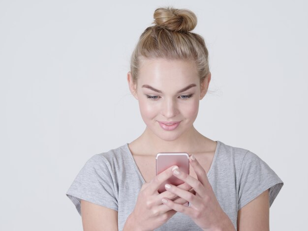 Attractive young woman holds mobile phone  - at studio