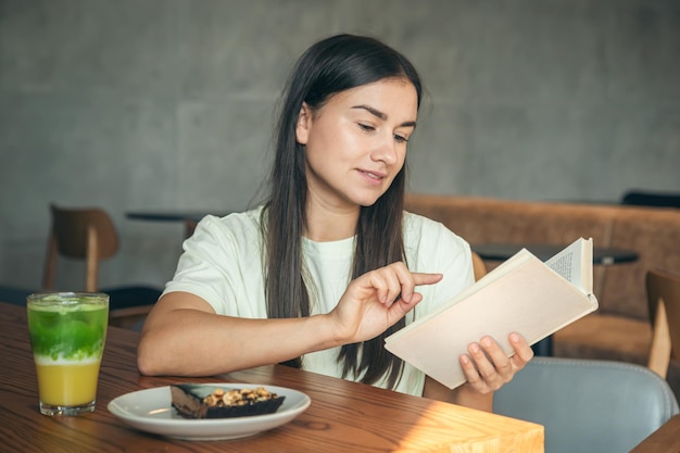 Attractive young woman is reading a book while sitting in a cafe
