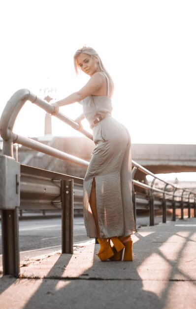 Привлекательная молодая женщина стоит на набережной в яркий солнечный день.