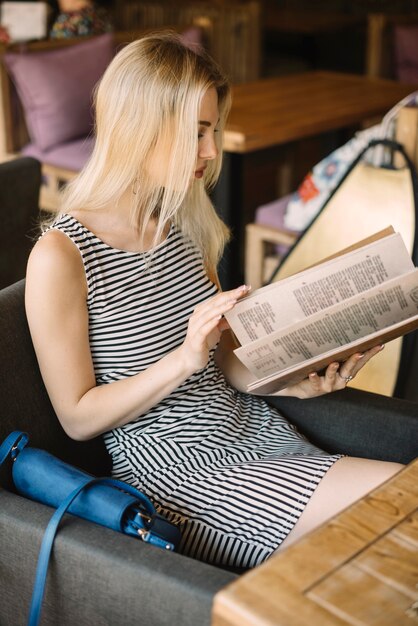 Attractive young woman looking at menu sitting in the restaurant