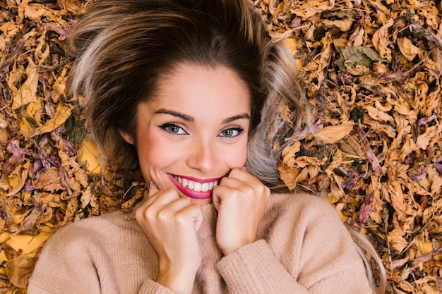 Attractive young woman lying on dry leaves and posing