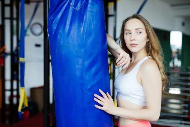 Free photo attractive young woman making a punch on the blue sandbag