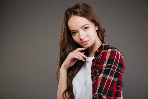 Attractive young woman in plaid shirt standing and posing