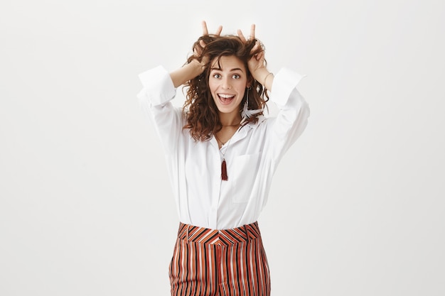 Attractive young woman in playful mood showing bunny ears on head