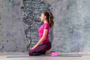 Free photo an attractive young woman practicing yoga against weathered wall